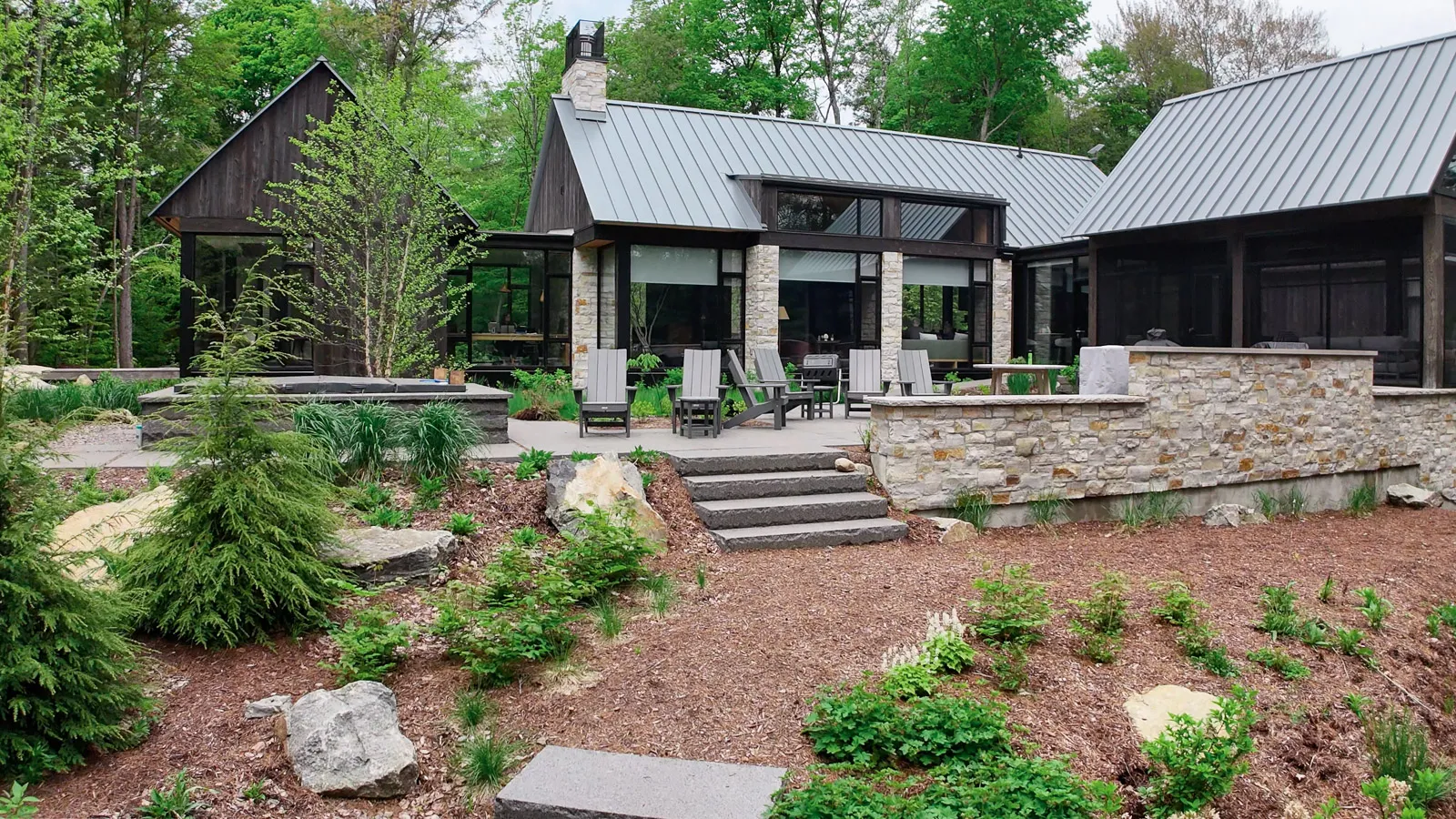 Precision cut granite patio with custom built outdoor kitchen and in ground hot tub surrounded by professional landscaping.
