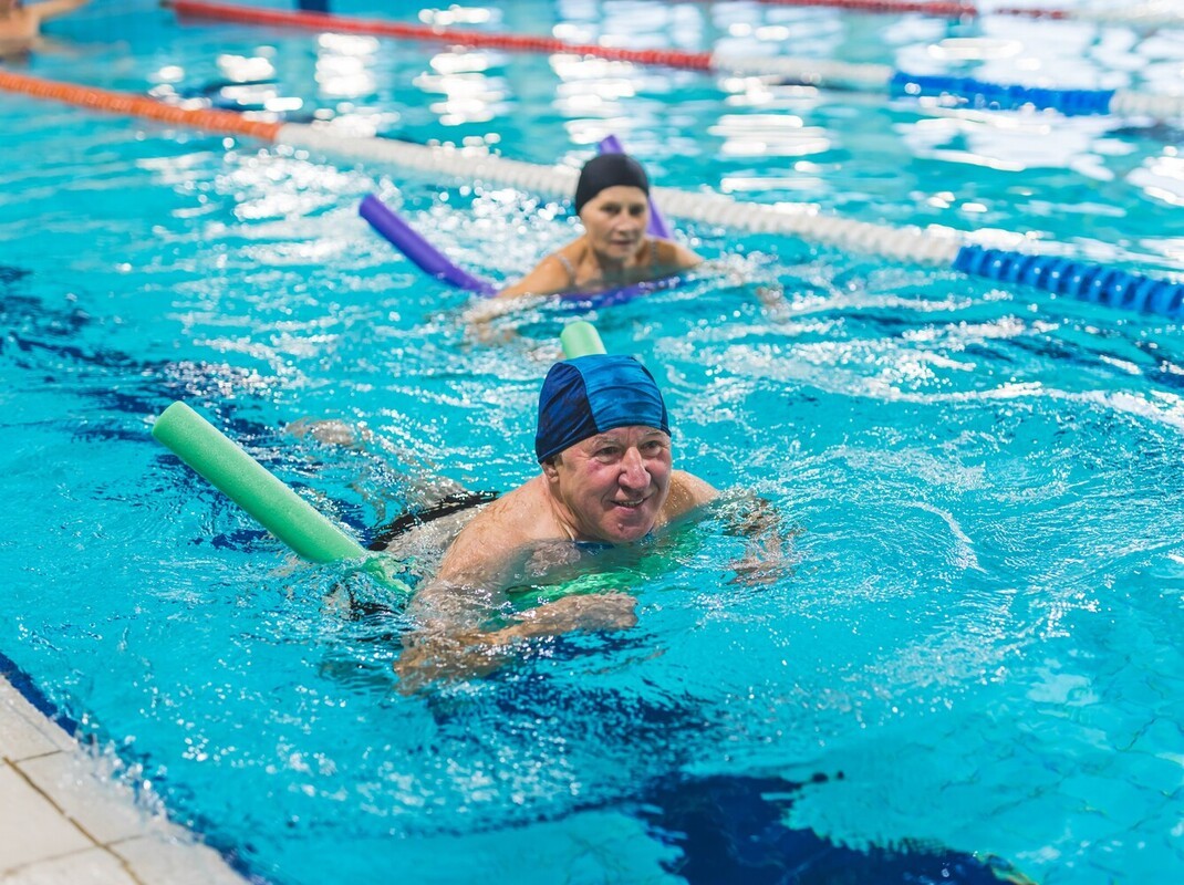 older couple increasing their calorie burn by using aids to learn how to lose weight swimming