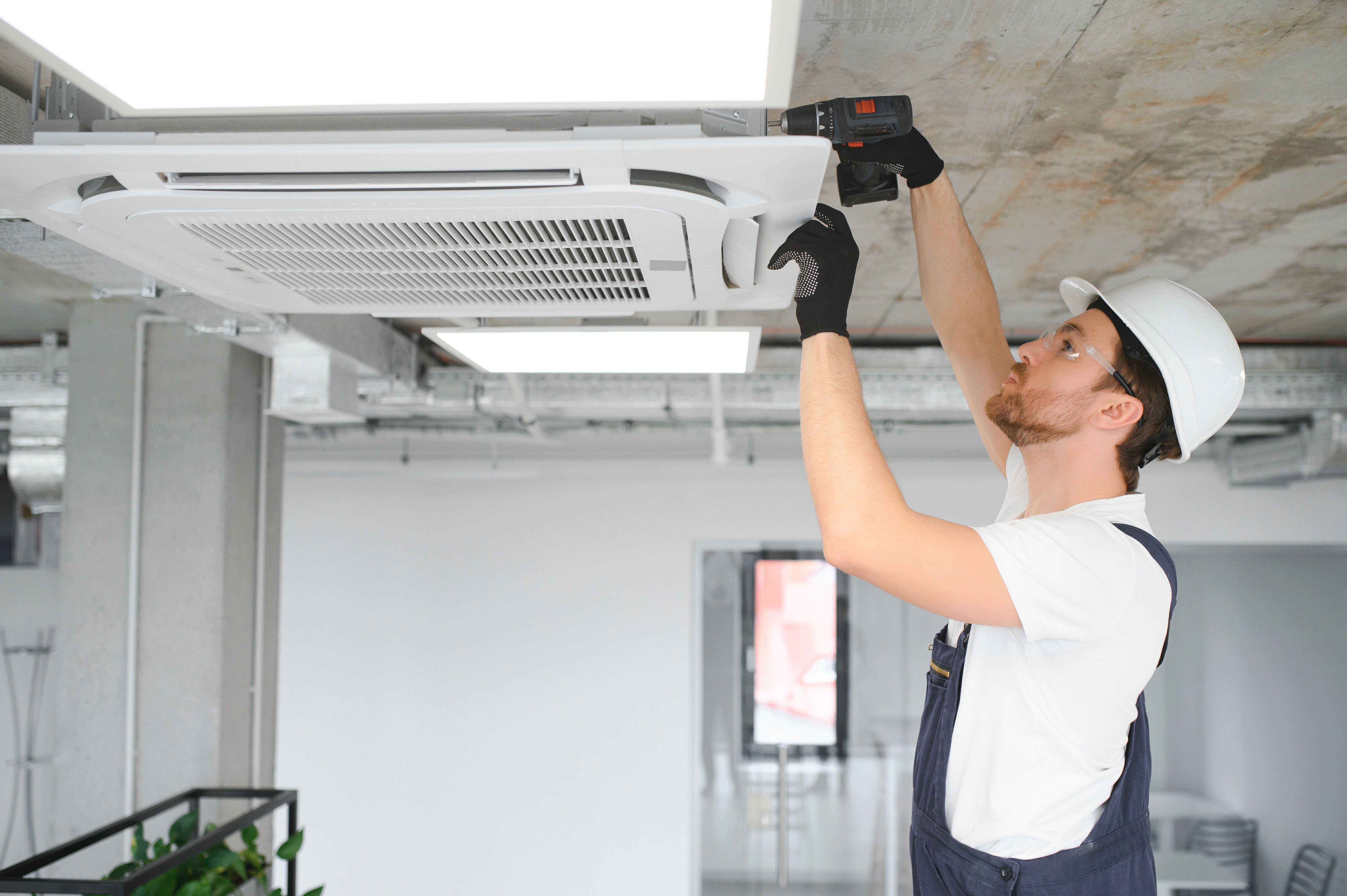 Technician servicing a ceiling-mounted air conditioning unit