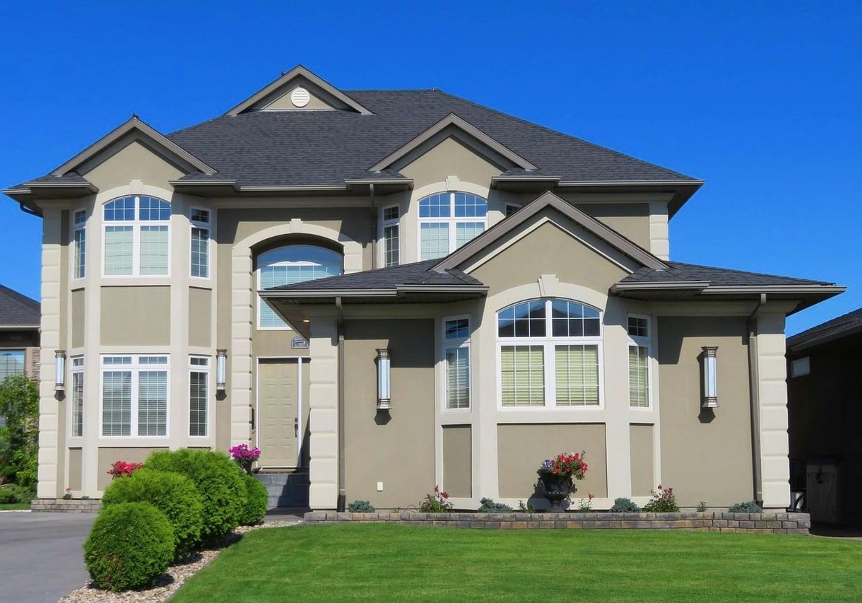 Residential real estate in a suburb, featuring a double storey home with blue skies in the background and a green garden in the foreground