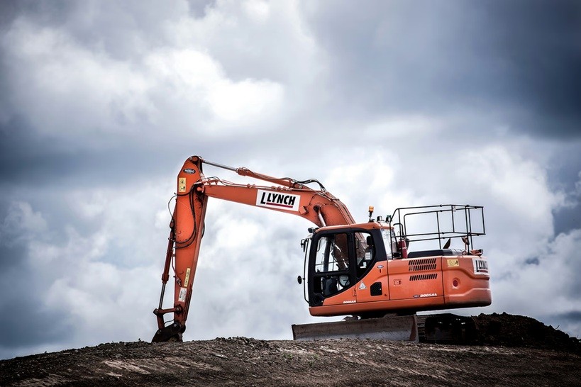 Orange excavator parked on a construction site hilltop
