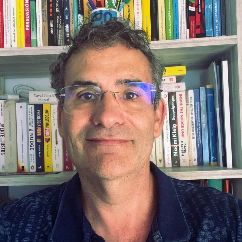 Retrato de Manuel Armayones, catedrático en diseño del comportamiento y profesor universitario, experto en salud digital, frente a una estantería con libros.