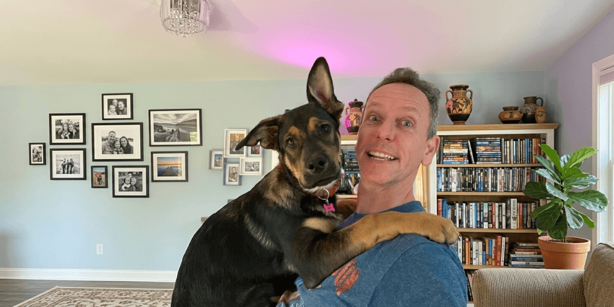 James Conroy holds a young puppy inside a home, highlighting the human-dog bond.