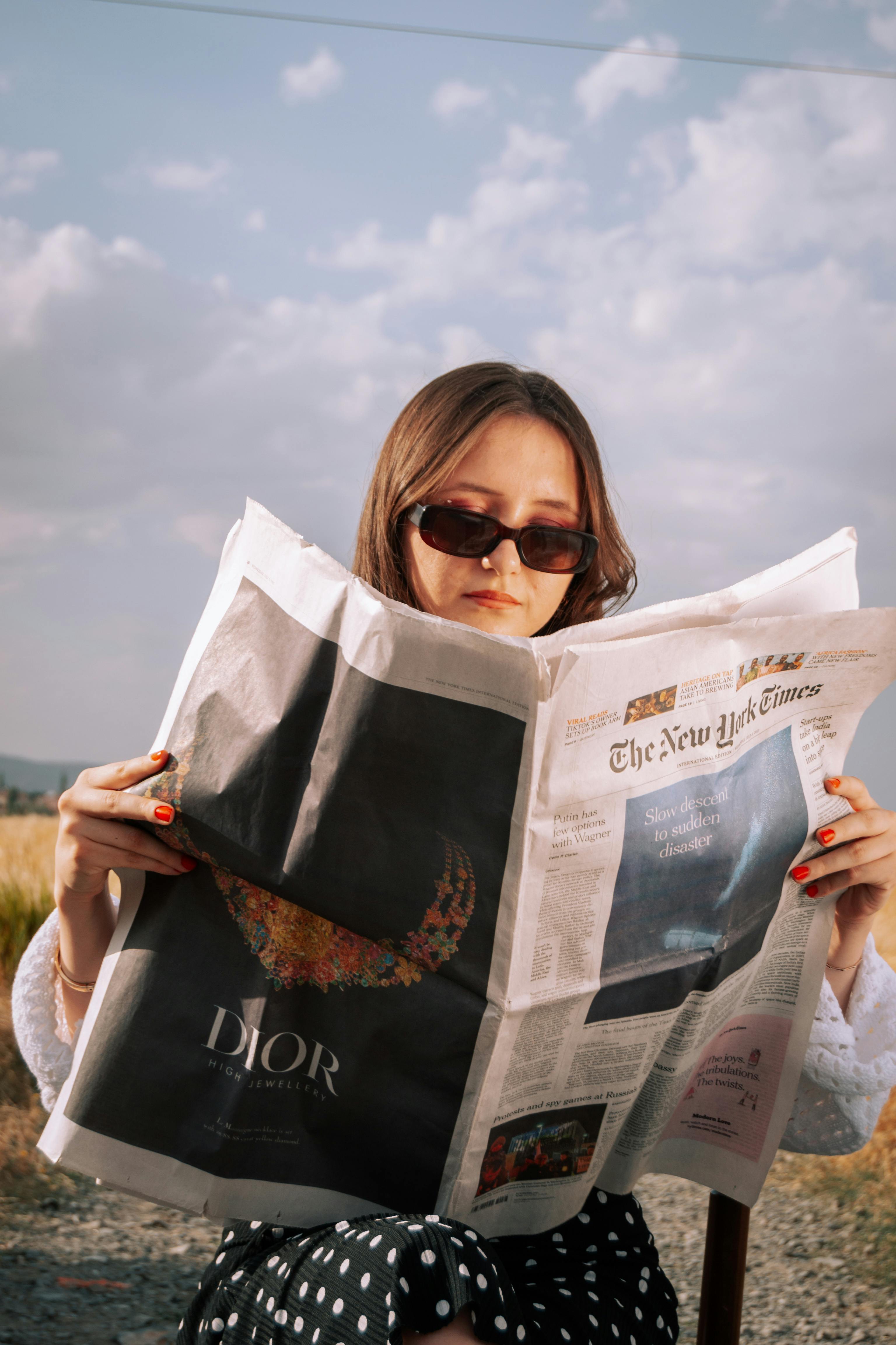 woman-enjoys-a-sunny-day-reading-a-newspaper-outdoors,-wearing-sunglasses. - ömer-derinyar (pexels)
