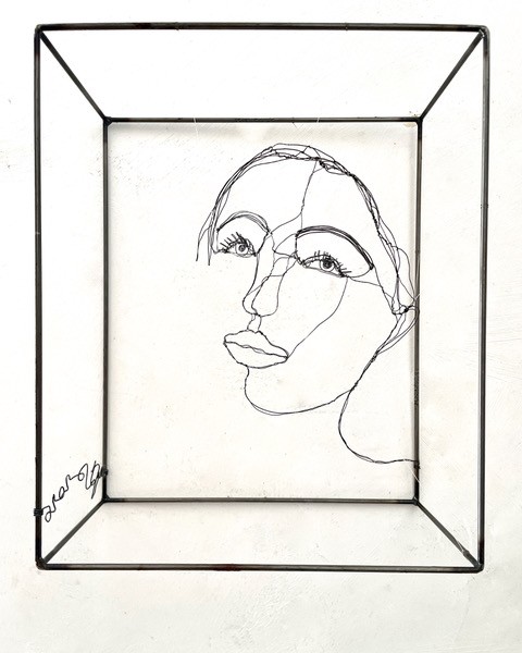 Sculpture en fil de fer représentant le visage d'une femme dans un cadre en fil de fer, vue détaillée de face
