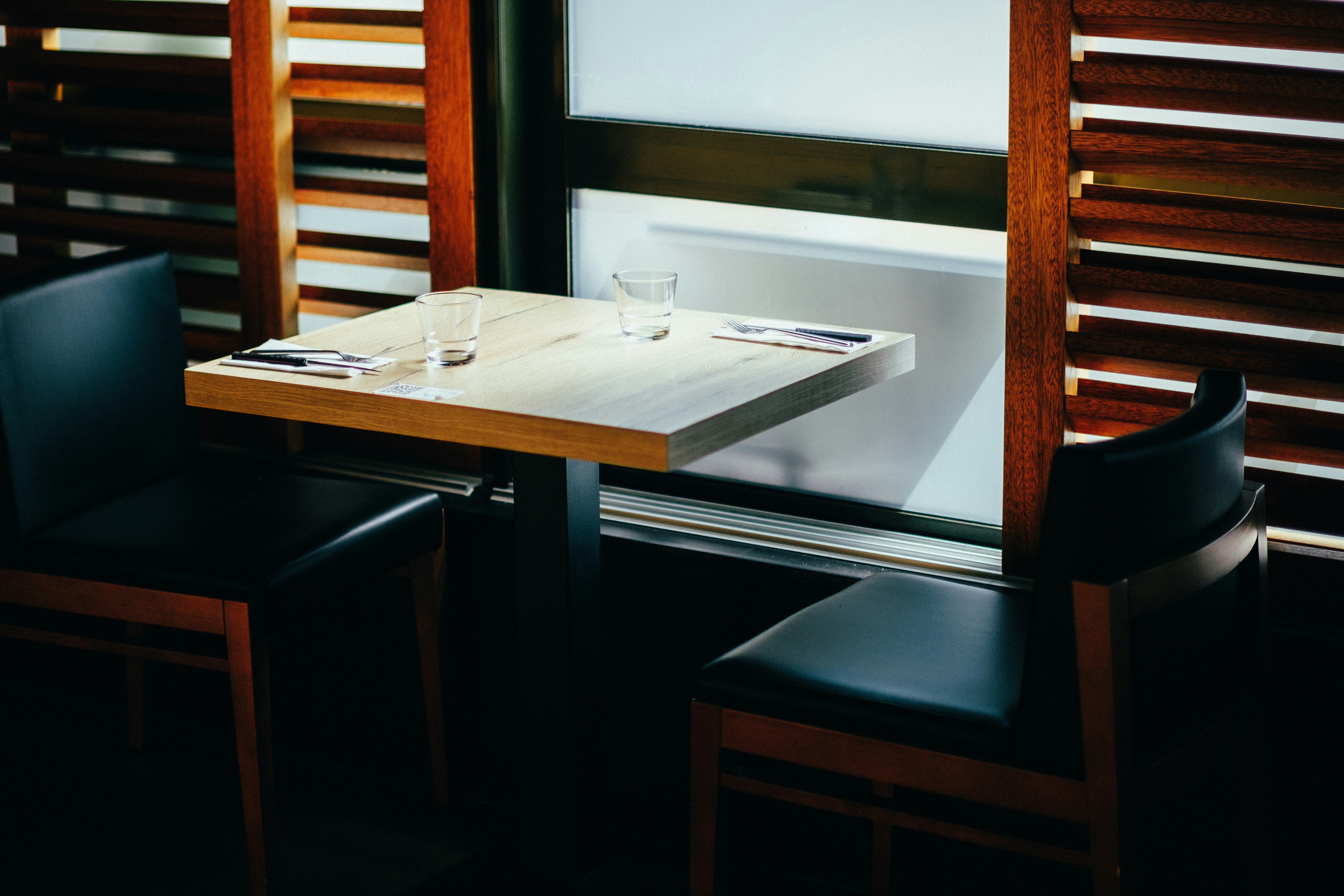 a table with two glasses on it in front of a window