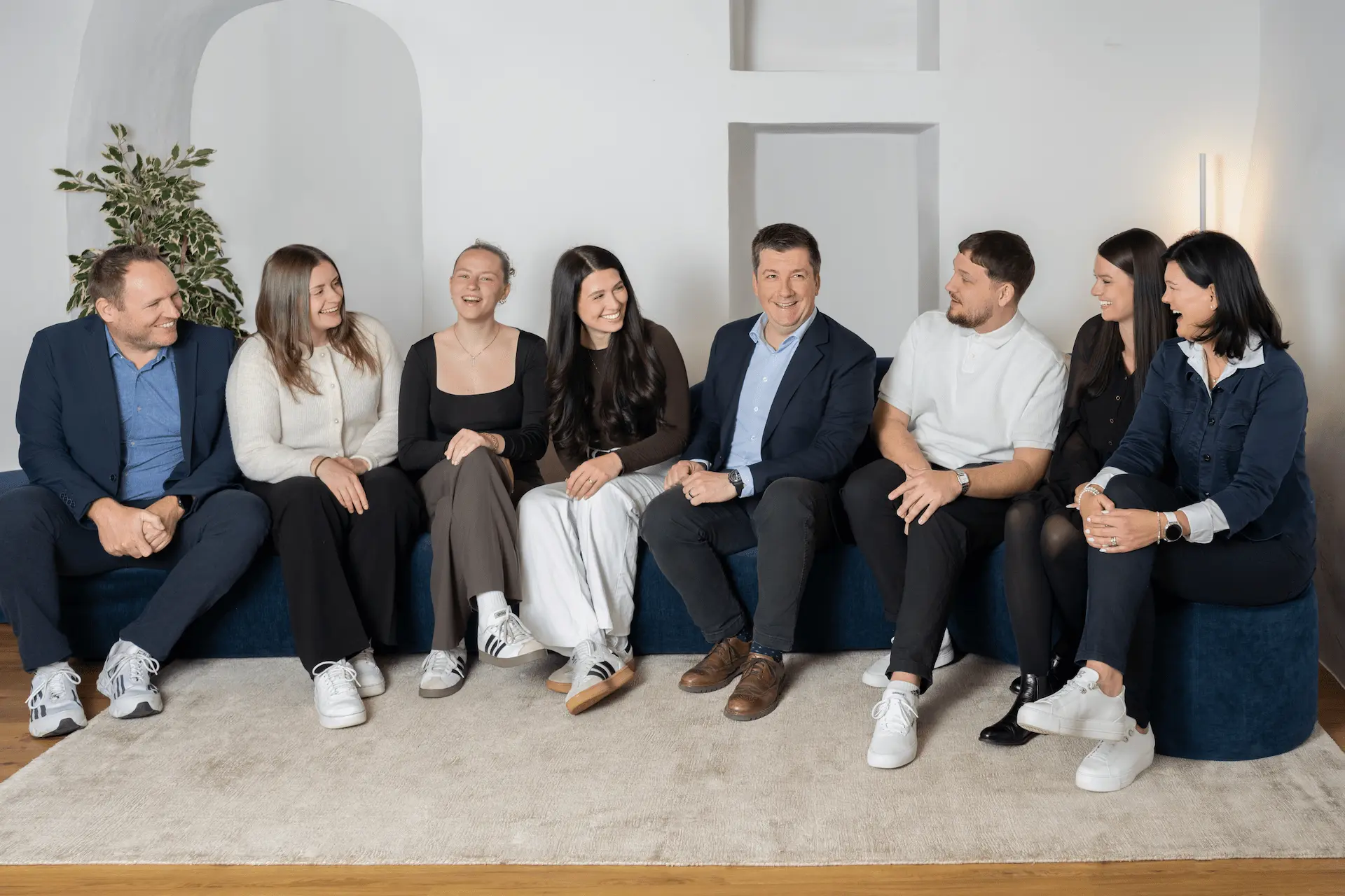 Gesamtes Team von Kocher Immobilien sitzt gemeinsam im Büro und lacht in moderner Umgebung