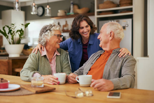 A daughter with her hands over the shoulders of her elderly parents, smiling