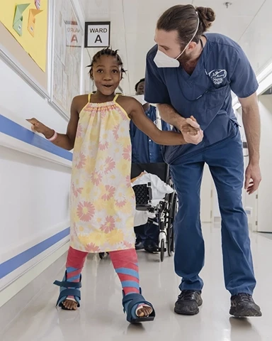 Volunteer man helping a child walk