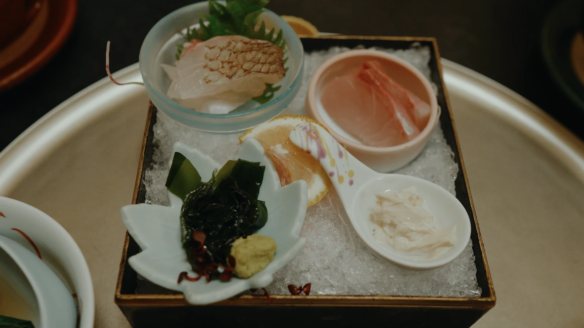 Sashimi and small dishes on a lacquer tray over ice at Kurokawa Onsen