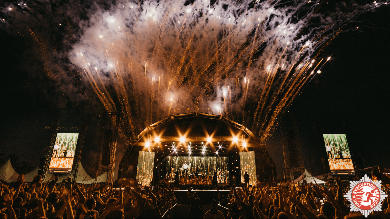 A festival crowd and stage with fireworks.