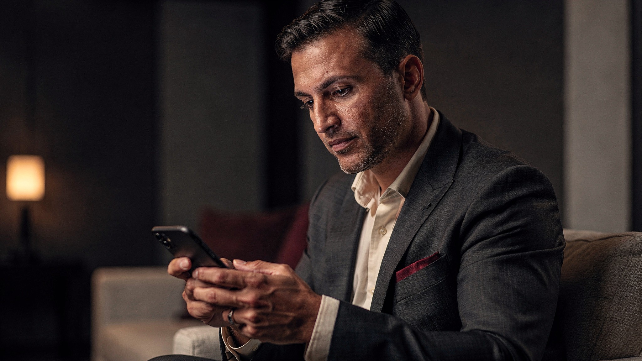 Creator looking thoughtfully at a phone in a dim room, ai influencer common mistakes