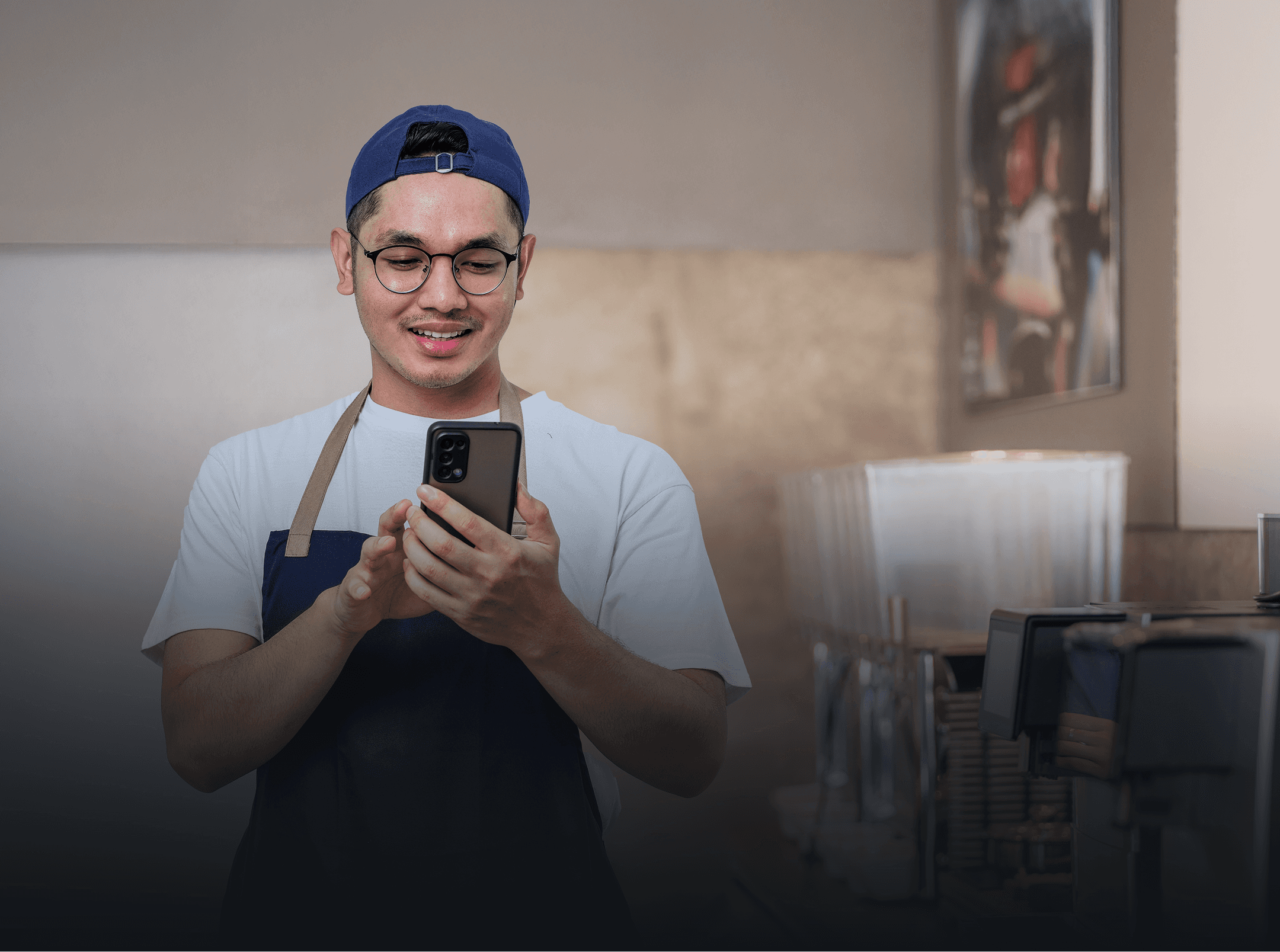 Two women are standing side by side against a beige wall, smiling confidently, one wearing a green shirt and the other in a dark blazer, with soft lighting casting gentle shadows.