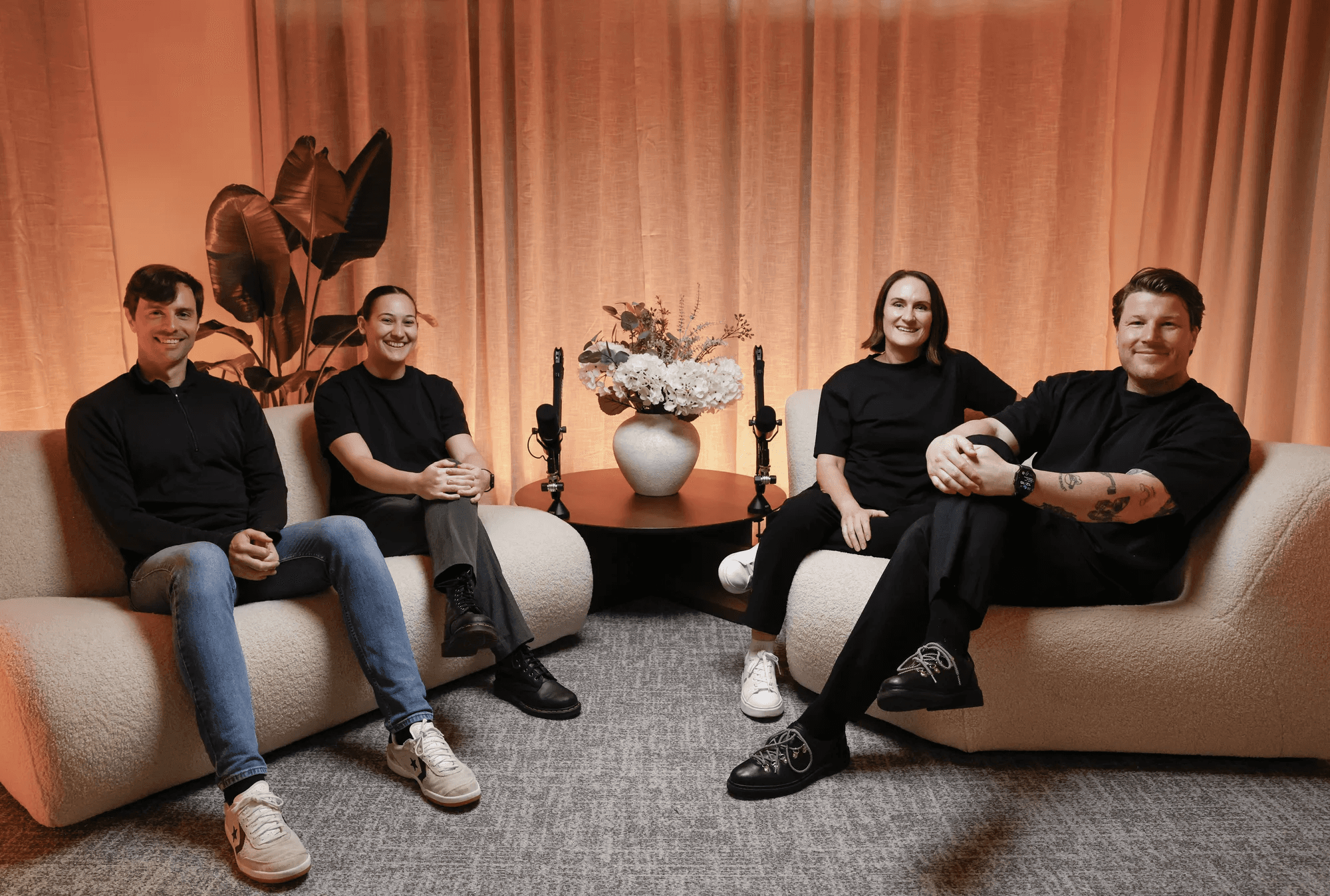 The Session in Progress team of four seated on bouclé sofas in a warmly lit studio