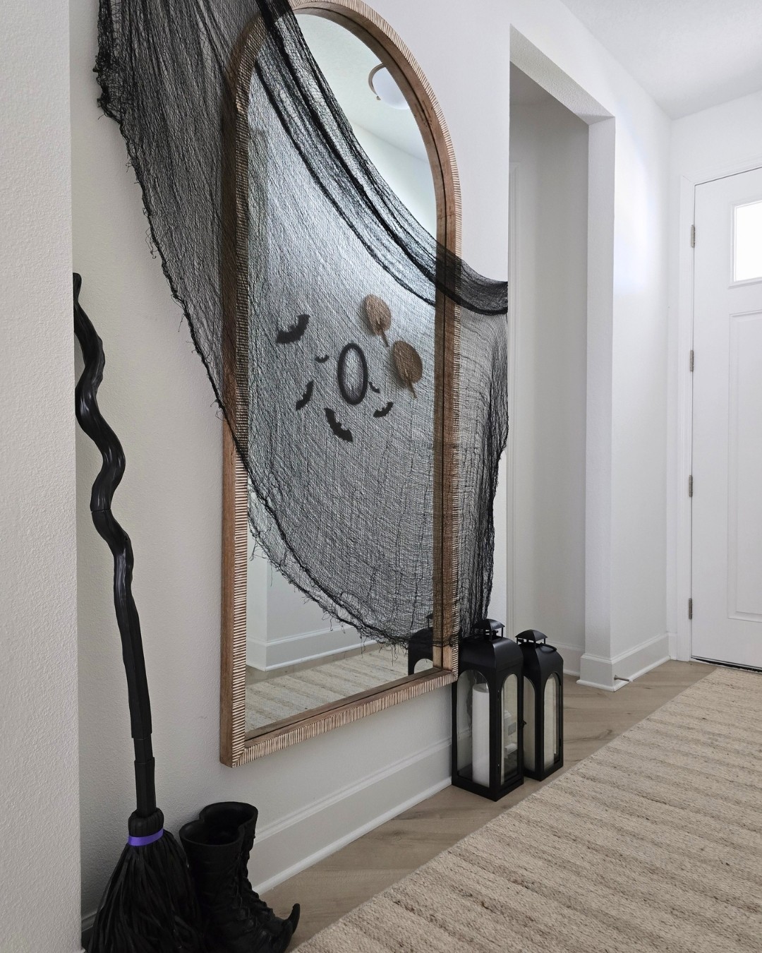 Halloween entry decor with black gauze, witch's boots and broomstick and lanterns