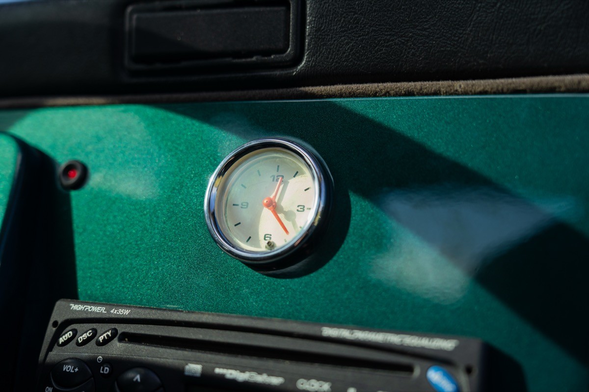 Close-up of a gauge on a green dashboard, with a visible needle indicating a measurement.