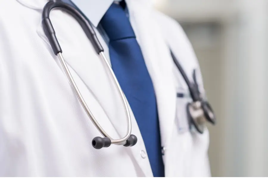 Pharmacy safety platforms symbolized by a close-up of a doctor’s white coat and stethoscope in a clinical setting.