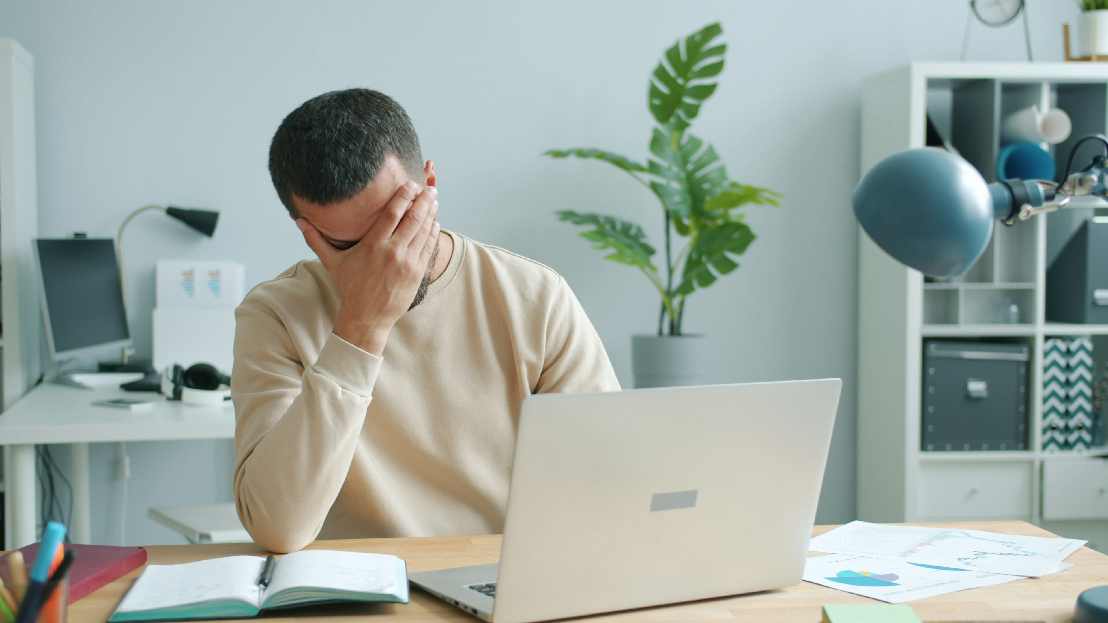 Man rubbing his face in front of laptop.