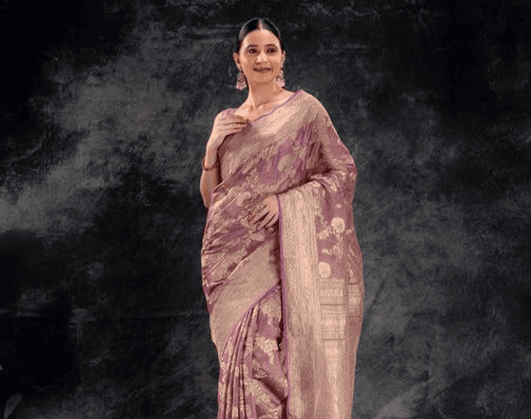 A woman wearing a peach tissue saree with a golden border from That Saree Shop, radiating a soft sheen and luxurious texture that captures timeless elegance and traditional charm.
