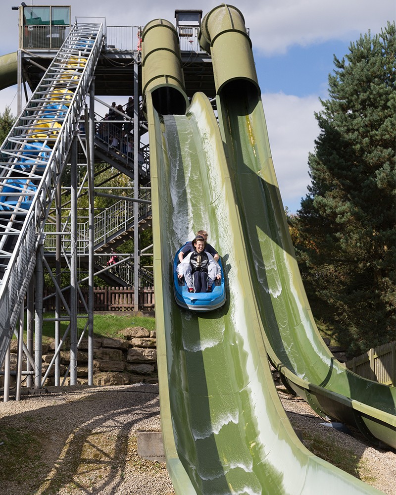 Water slide attraction with bright green chutes and log flumes carrying riders