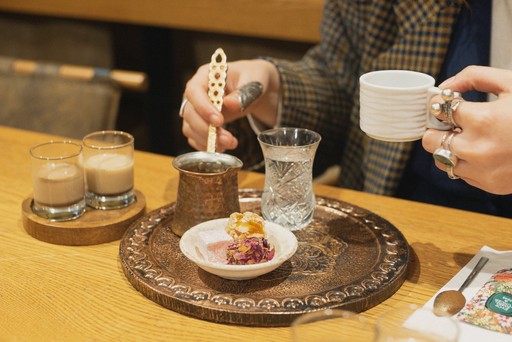 A close-up of a beautifully arranged tray with Turkish coffee, a glass of water, and a dessert, showcasing the complete serving setup typical in Turkish coffee culture.