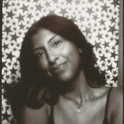 A thoughtful young person with dark hair gazes to the side, captured in soft black and white lighting.