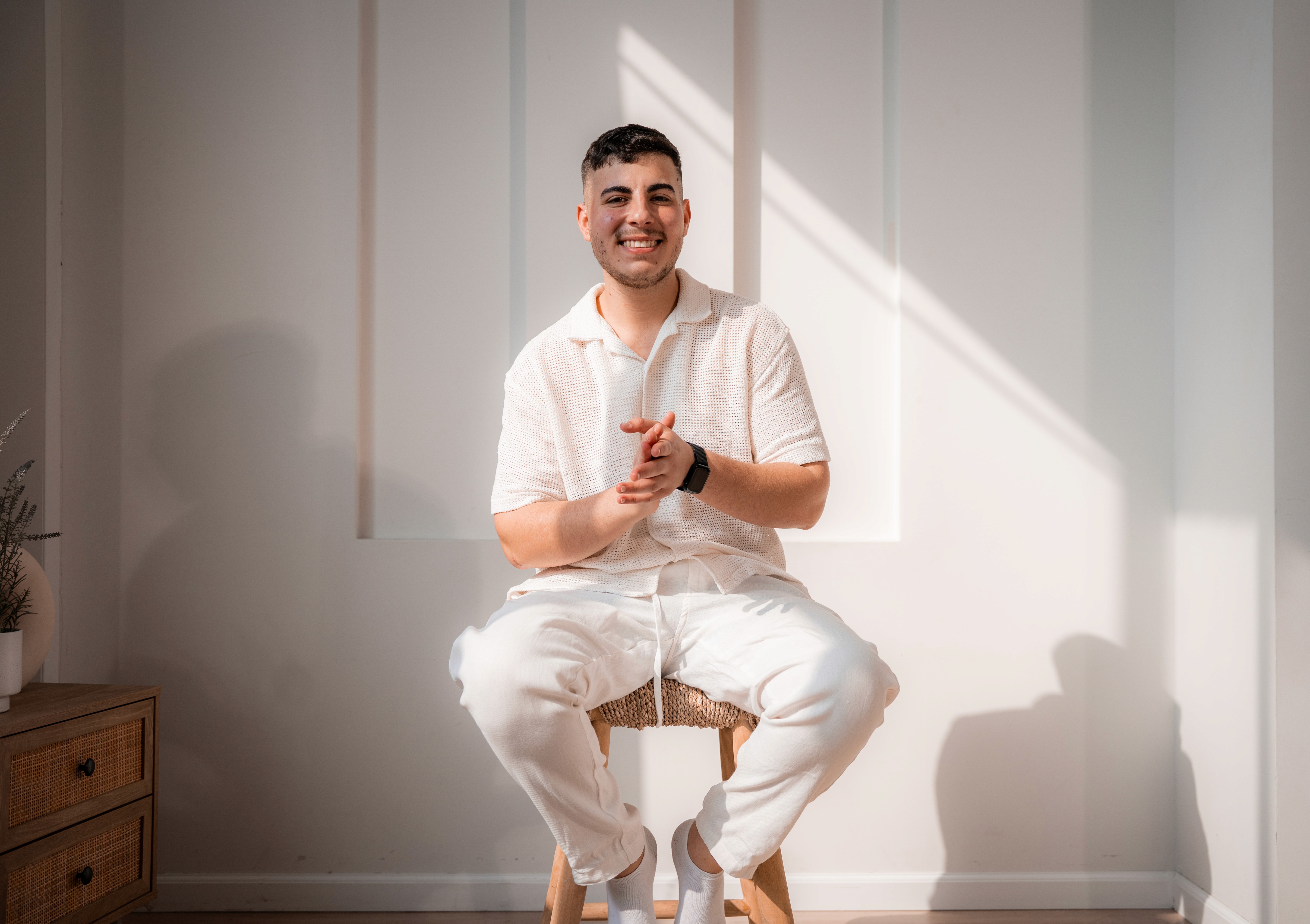 smiling man sitting on gray rock at daytime