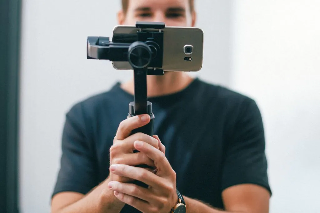 A young man holding a gimbal with a phone