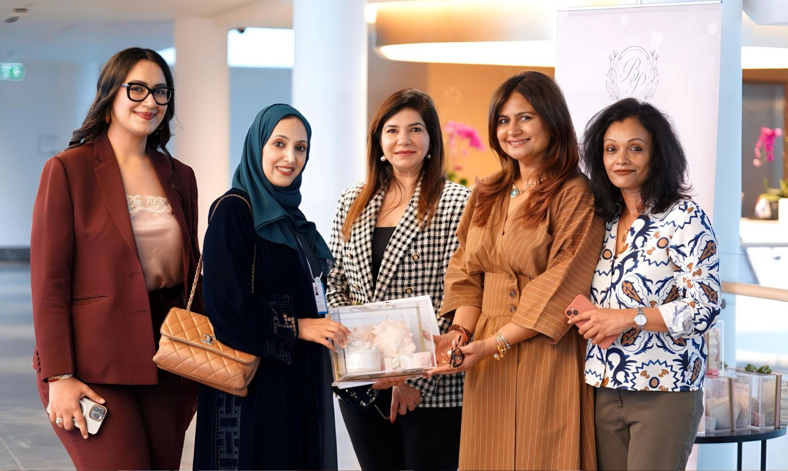 Five women holding an award at a business event