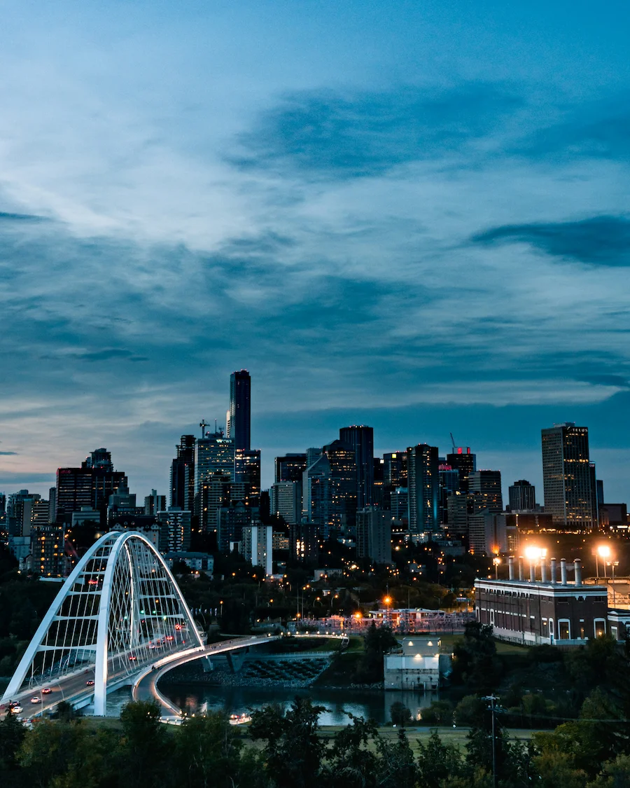 Evening view of Edmonton skyline with city lights and the Walterdale Bridge in the foreground