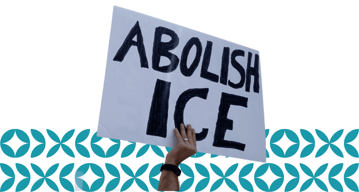 A hand holds up a protest sign in bold black lettering that reads "ABOLISH ICE," set against a clear sky background, symbolizing a call for immigration reform.