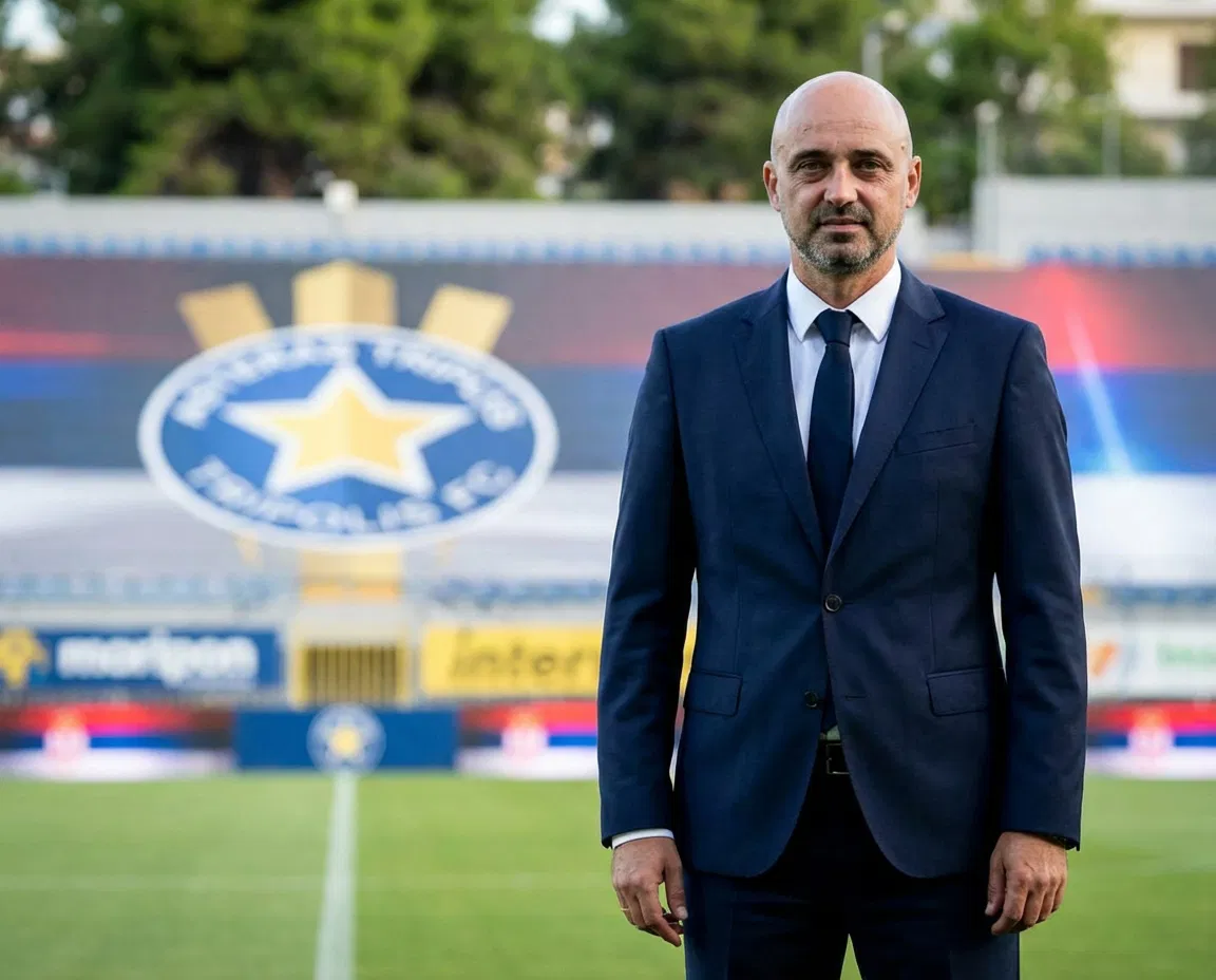 Portrait of Serbian coach Milan Rastavac standing in front of the Asteras Tripolis FC logo.