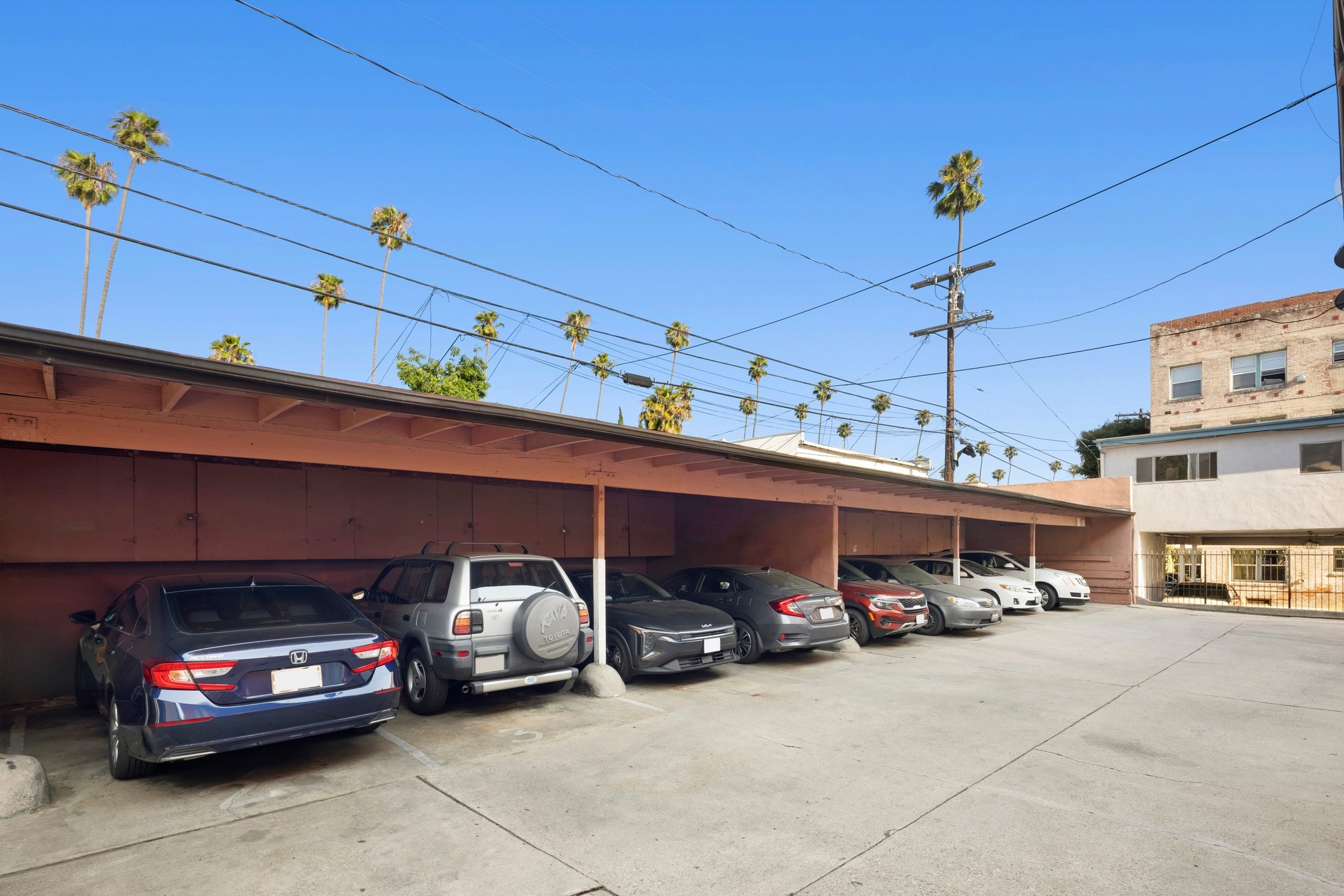 1640 N Harvard covered carport with multiple parked vehicles, palm trees, and residential building in background