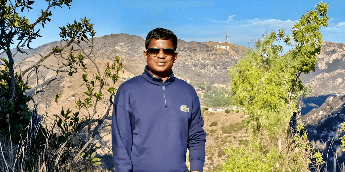Sai Kumar Medi, Indian entrepreneur turned Hollywood filmmaker, standing with the Hollywood sign in the background, exuding confidence