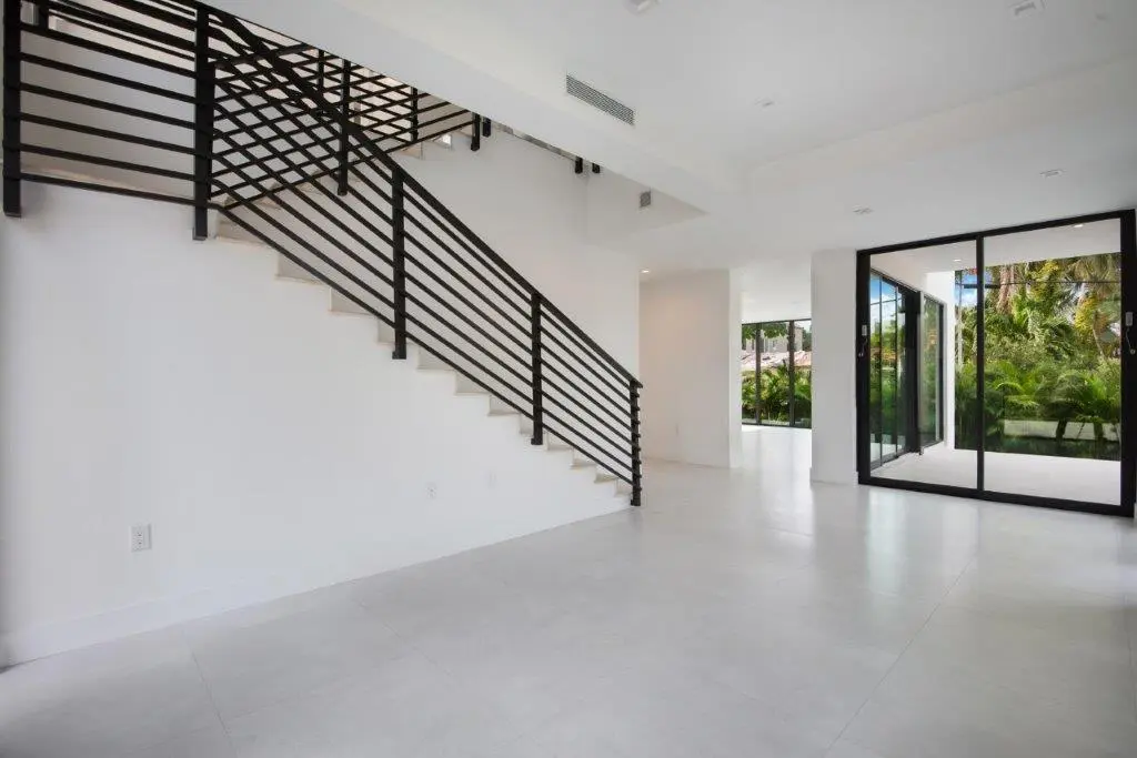 Modern interior staircase with black steel railing and open living area in Miami Beach home by Atelier International LLC
