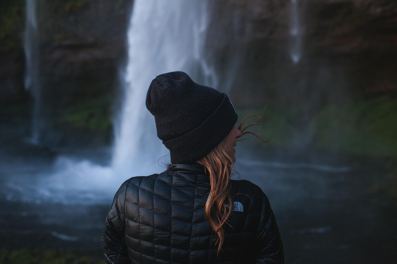 Person in coat standing by waterfall
