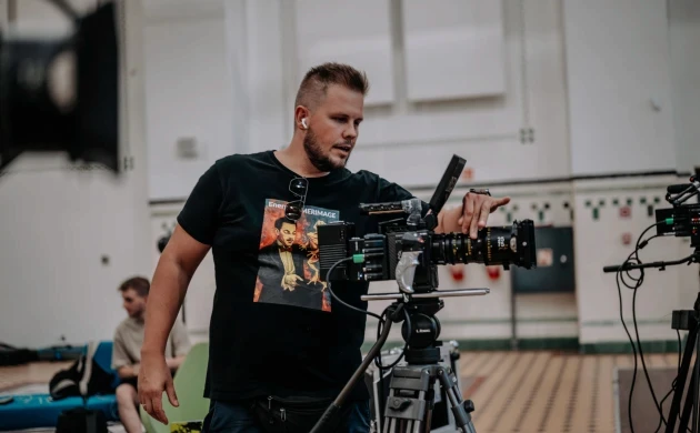 A filmmaker operating a cinema camera with a DZOFILM Arles zoom lens indoors
