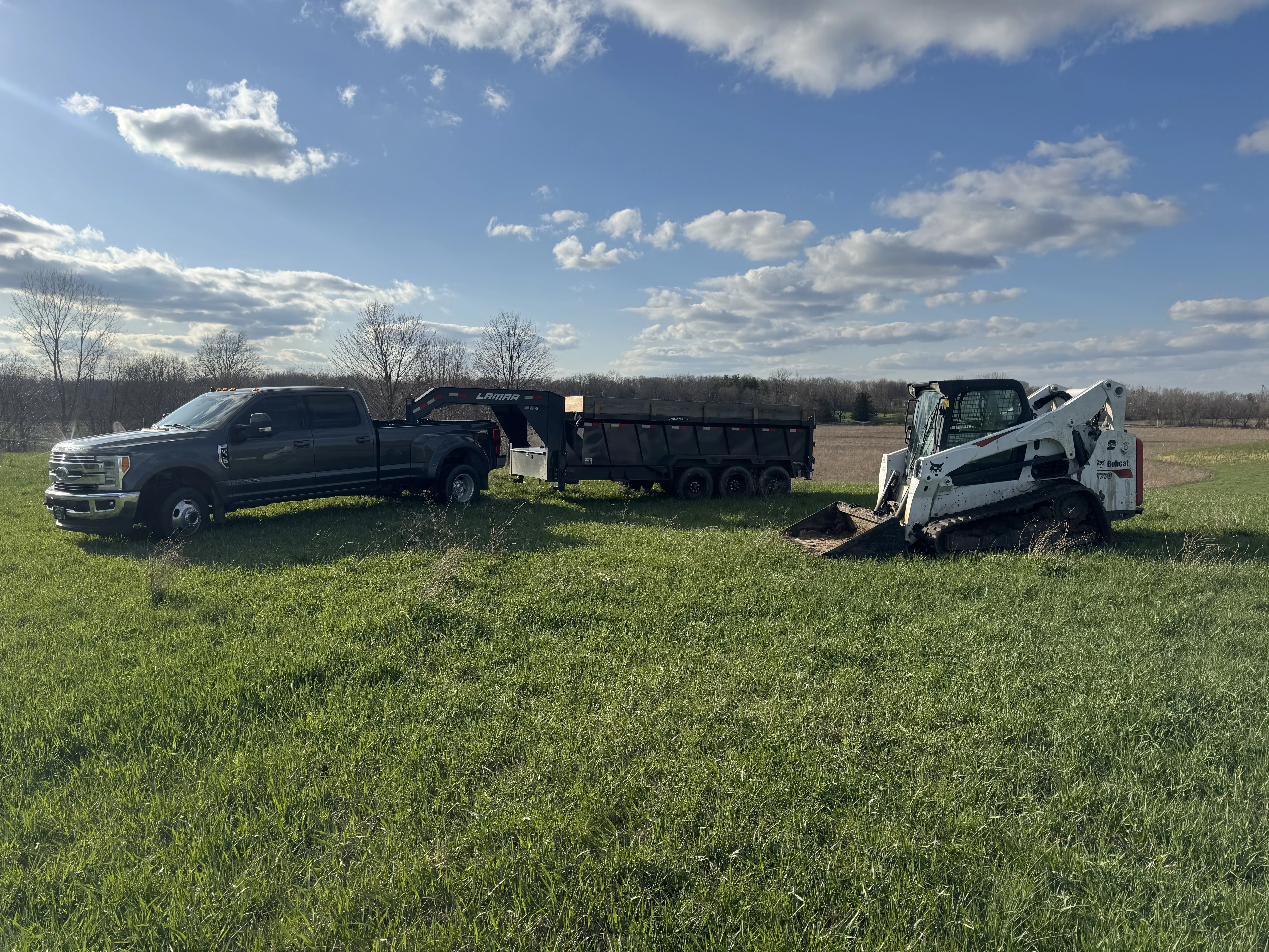 Skid steer loader moving dirt in a wooded area