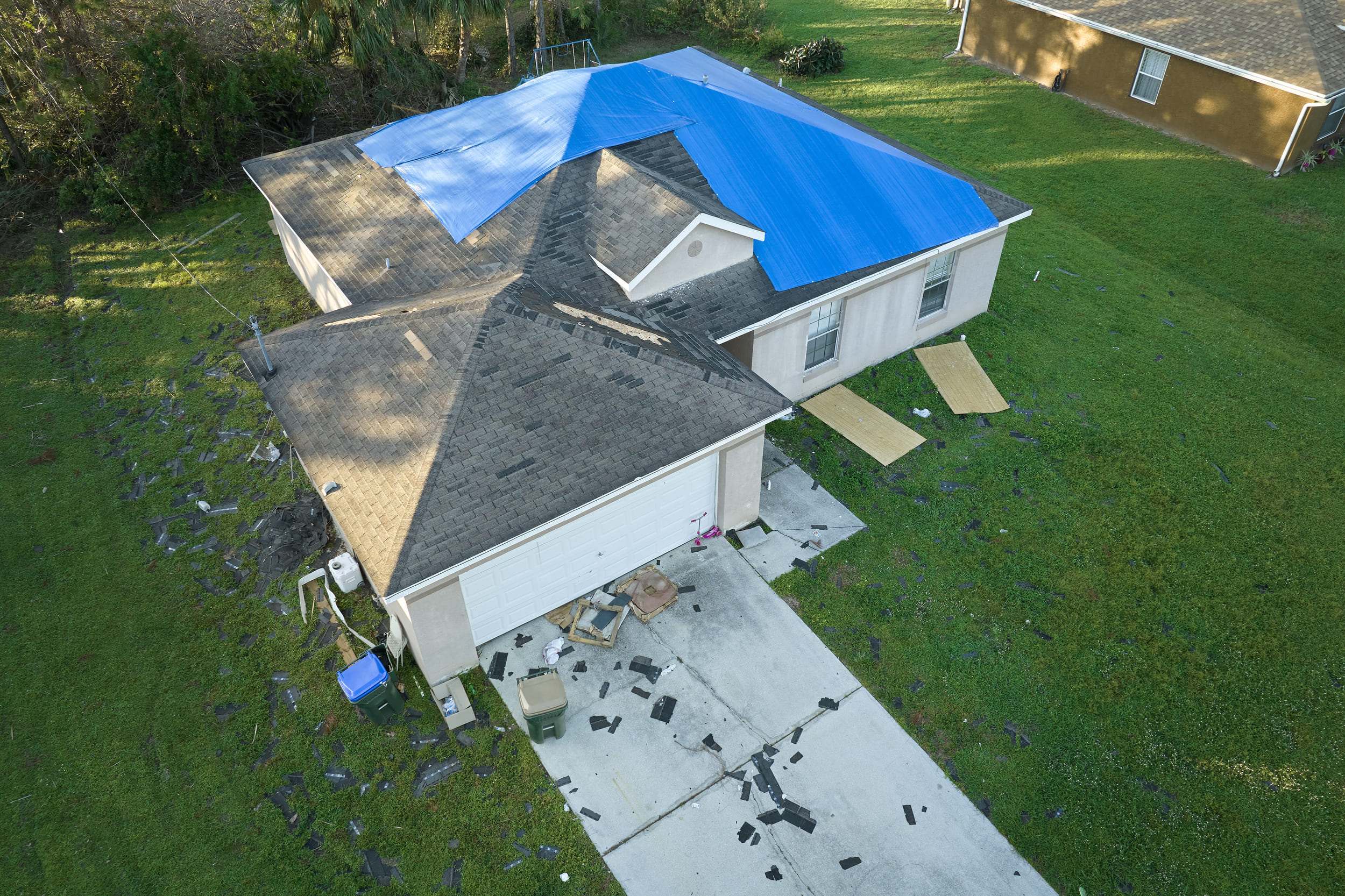 An image of a single-family home with roof damage, tarped to protect from further damage.