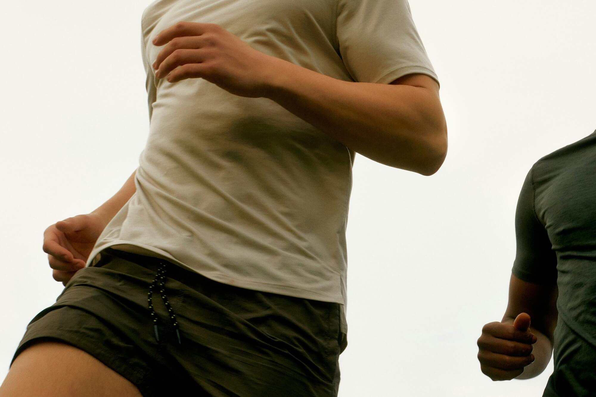 Two people are jogging, captured mid-stride from the waist up. The focus is on their motion and athletic attire, evoking energy and vitality.