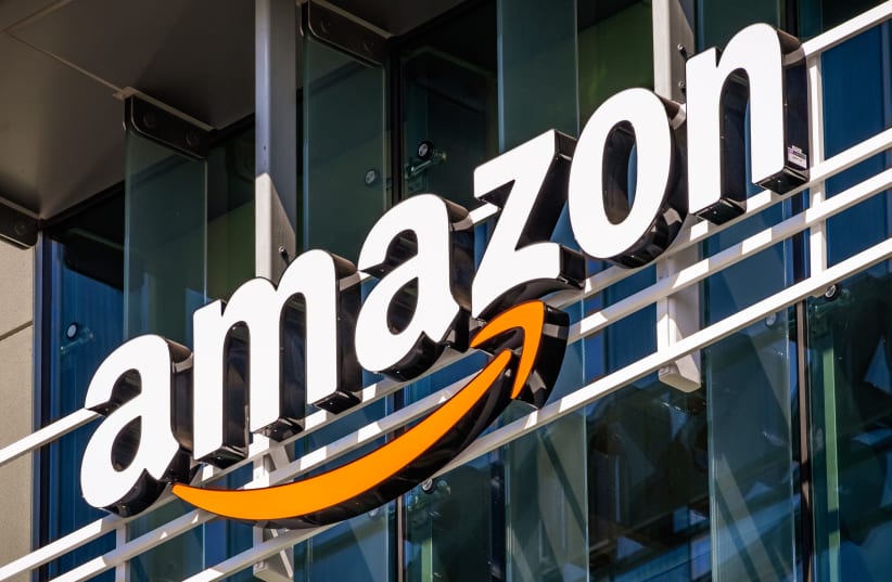 Amazon logo in bold letters with an orange arrow underneath, displayed on a sleek, white background against a glass-like building.