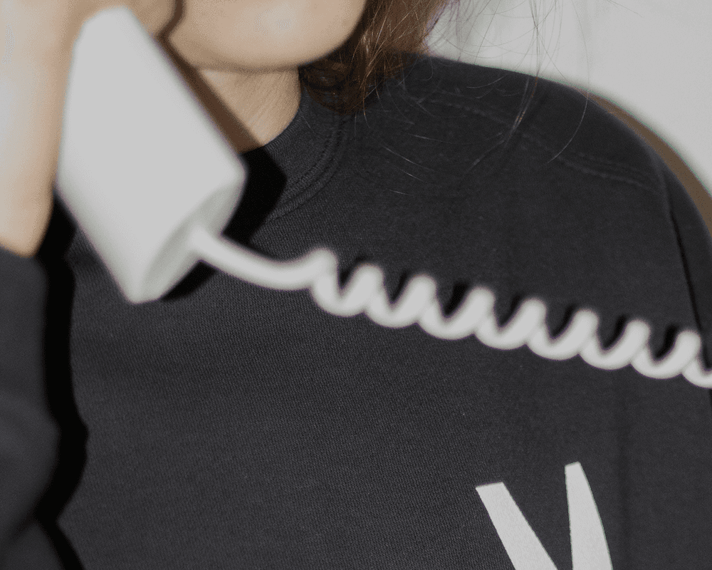 A close-up shot of a person in a black sweatshirt holding a white vintage-style telephone
