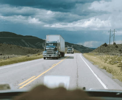 A truck moving on the road under the blue sky.