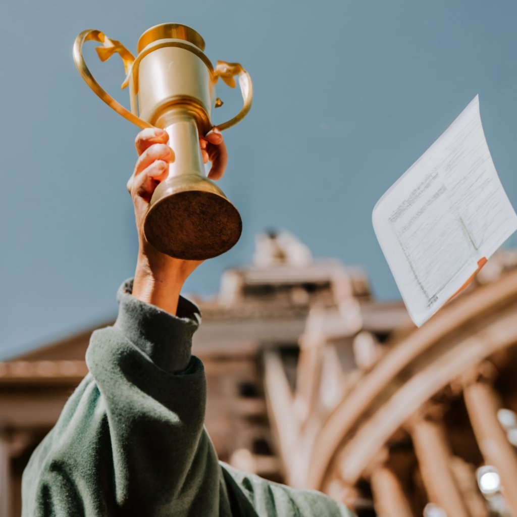 A person holding up an award or trophy, with U.S. immigration paperwork in the background, showcasing the extraordinary talent required for the O1 Visa