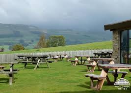 Scenic outdoor pub garden with wooden picnic tables overlooking tranquil rolling hills in countryside setting