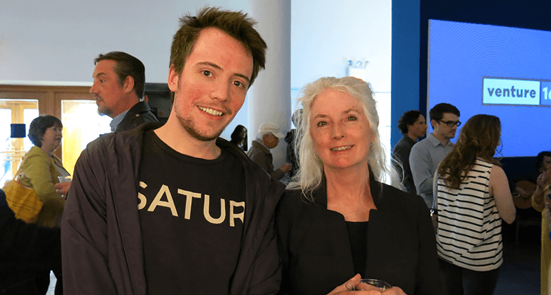 A photo of two people standing in an exhibition room among others.