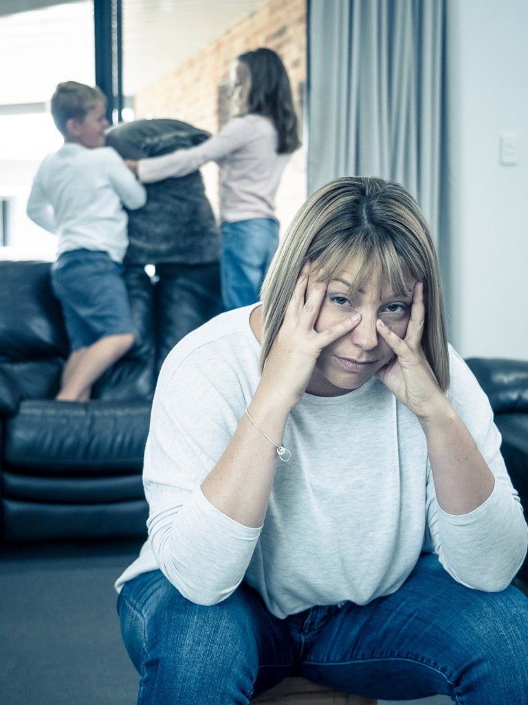 Tired mother sighing as her children make too much noise.