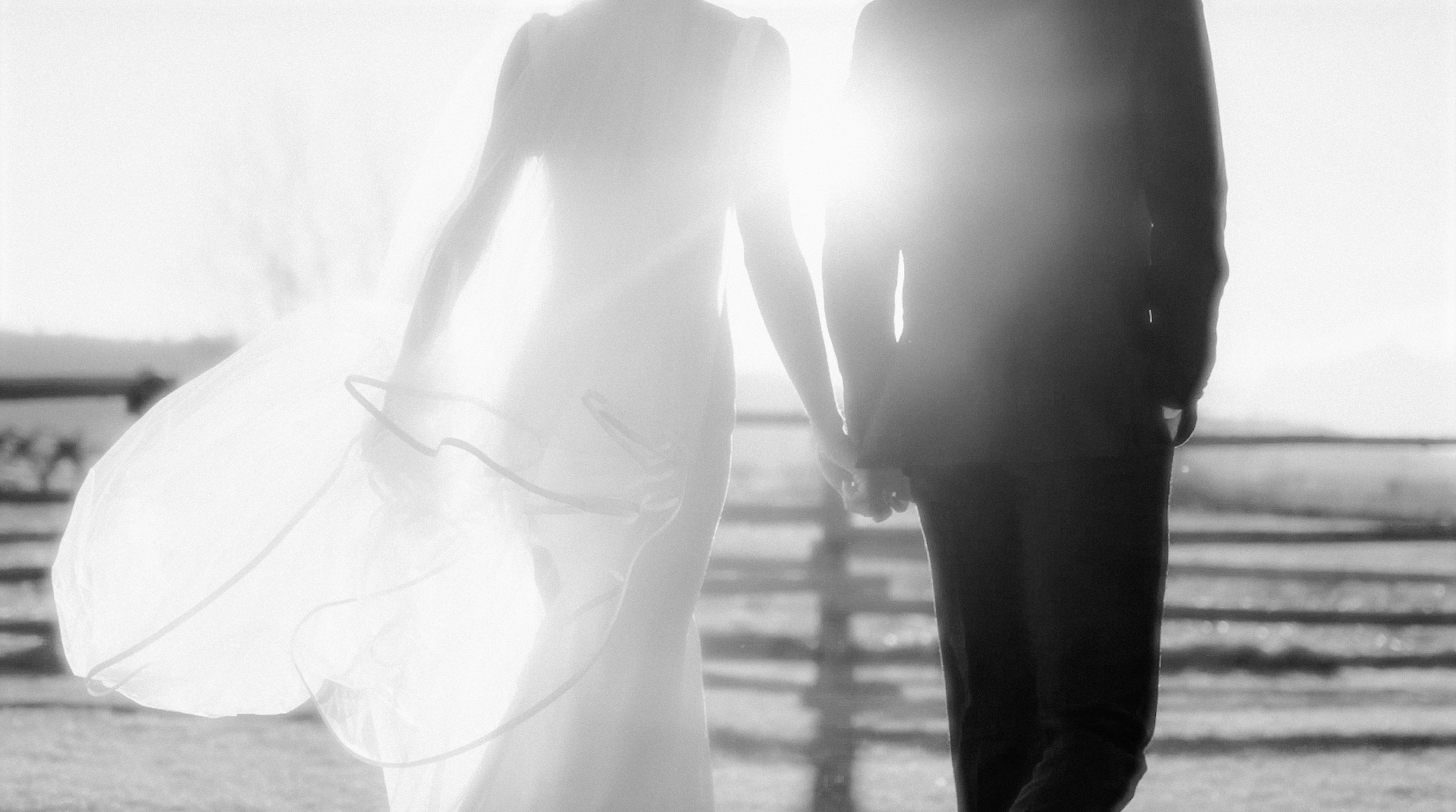 Bride and groom walking hand in hand outdoors.