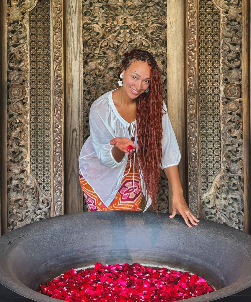 Man in apron stands in rustic kitchen, hands dusted with flour.