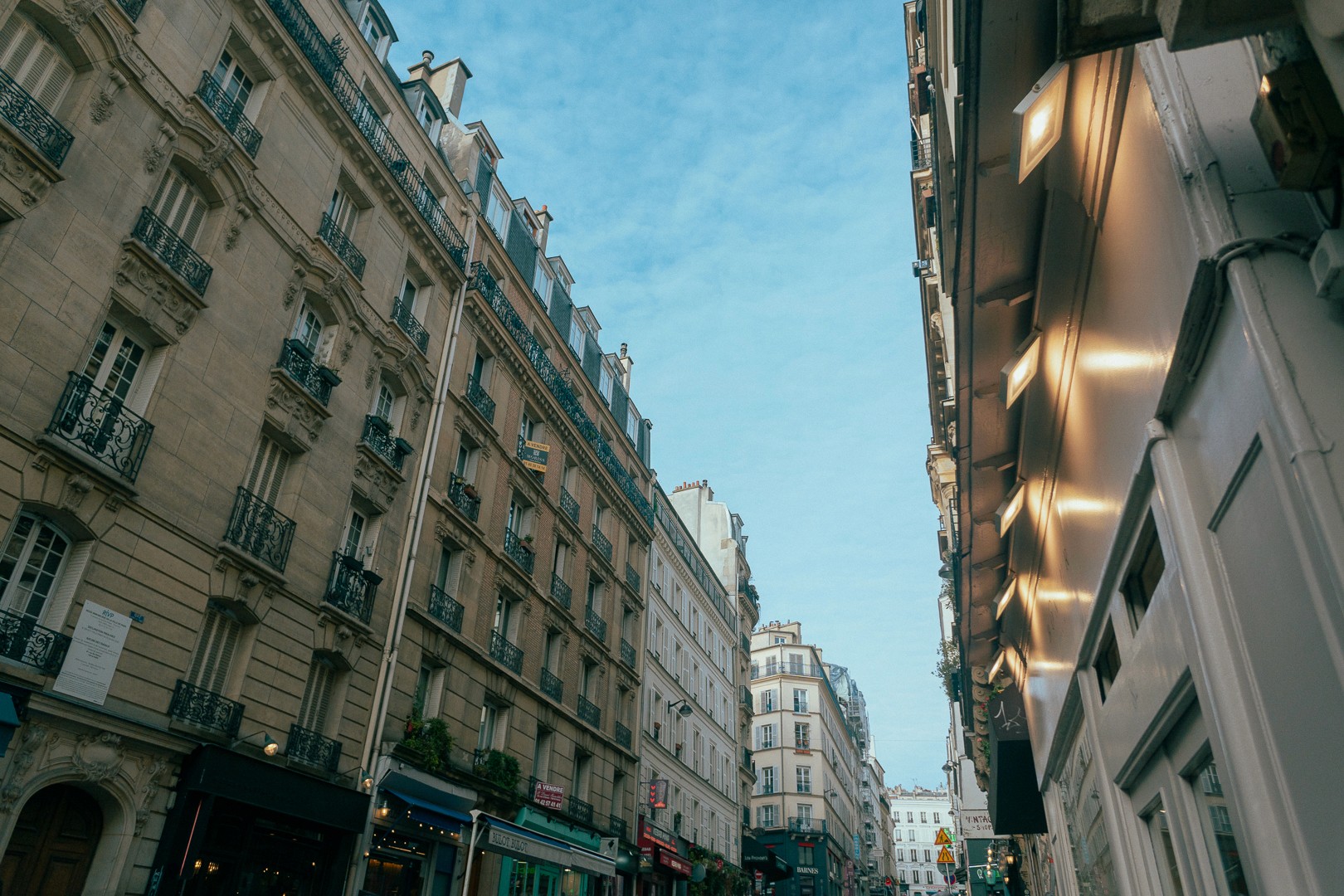 Façades d'immeubles typiques de Paris dans une rue étroite par une journée ensoleillée.